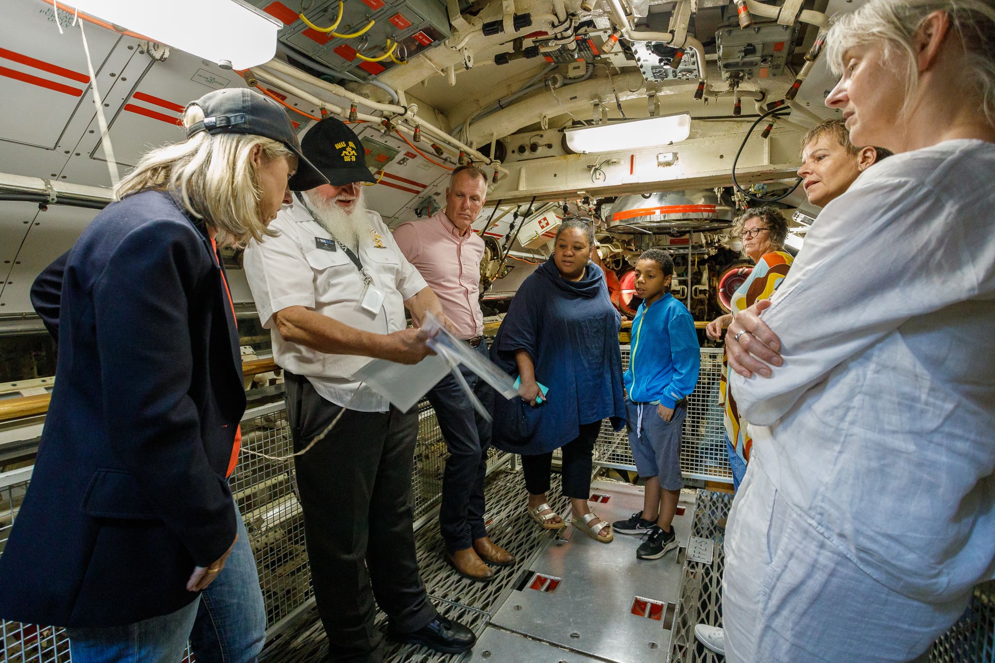 Group of people on tour inside submarine.