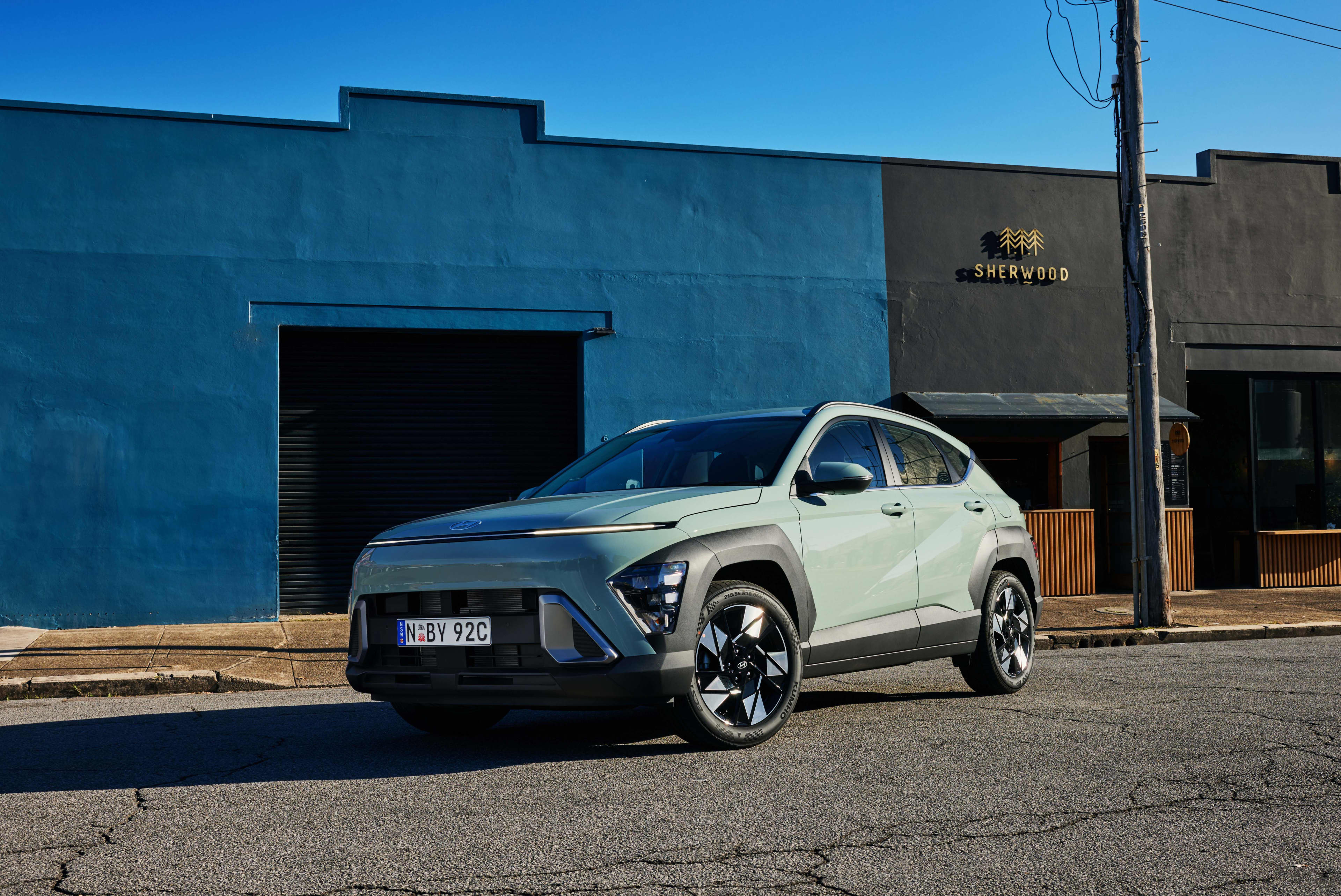 A mint green Hyundai Kona Elite parked outside a blue building.