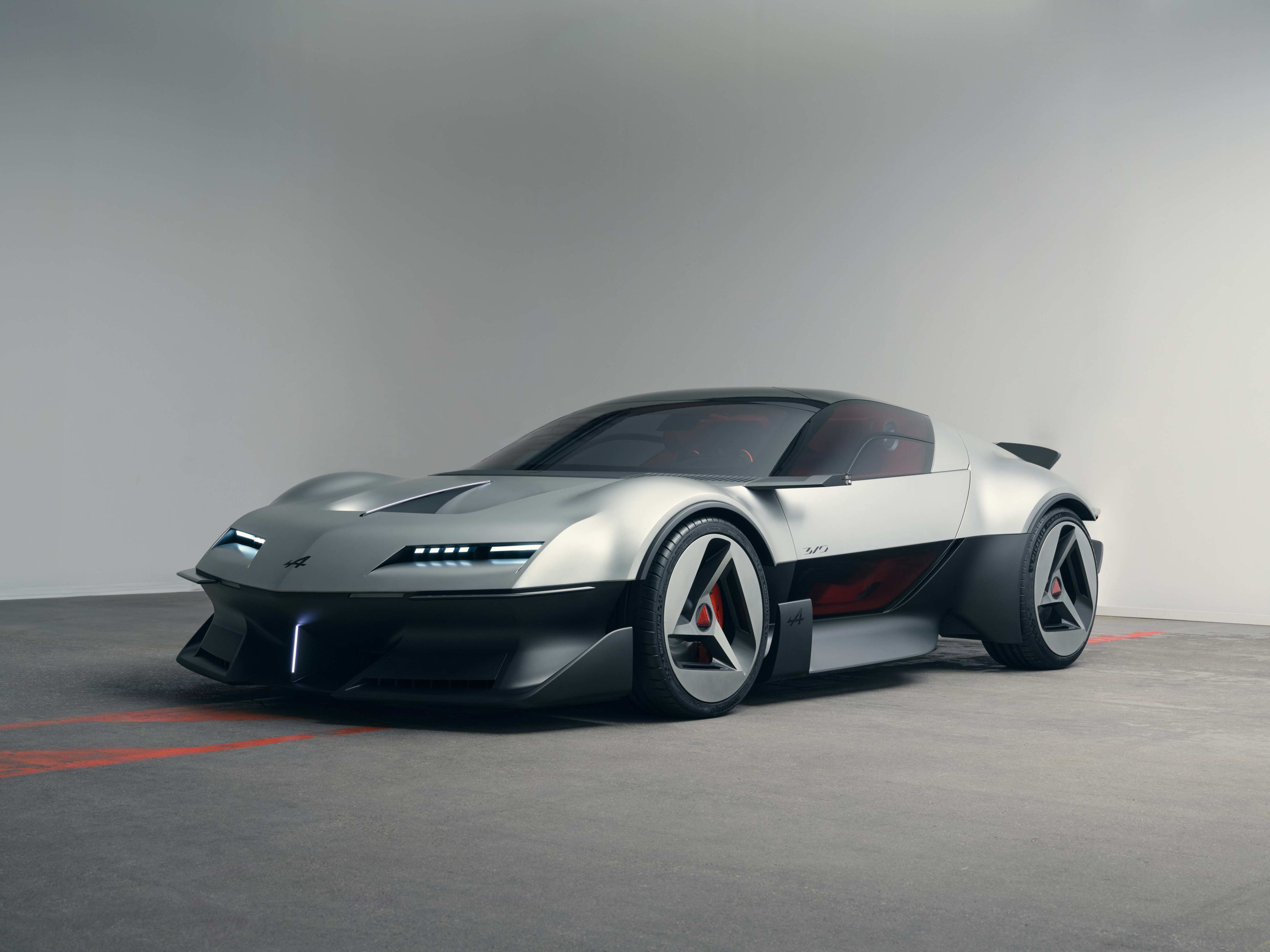 A futuristic silver sports car parked in a grey studio.