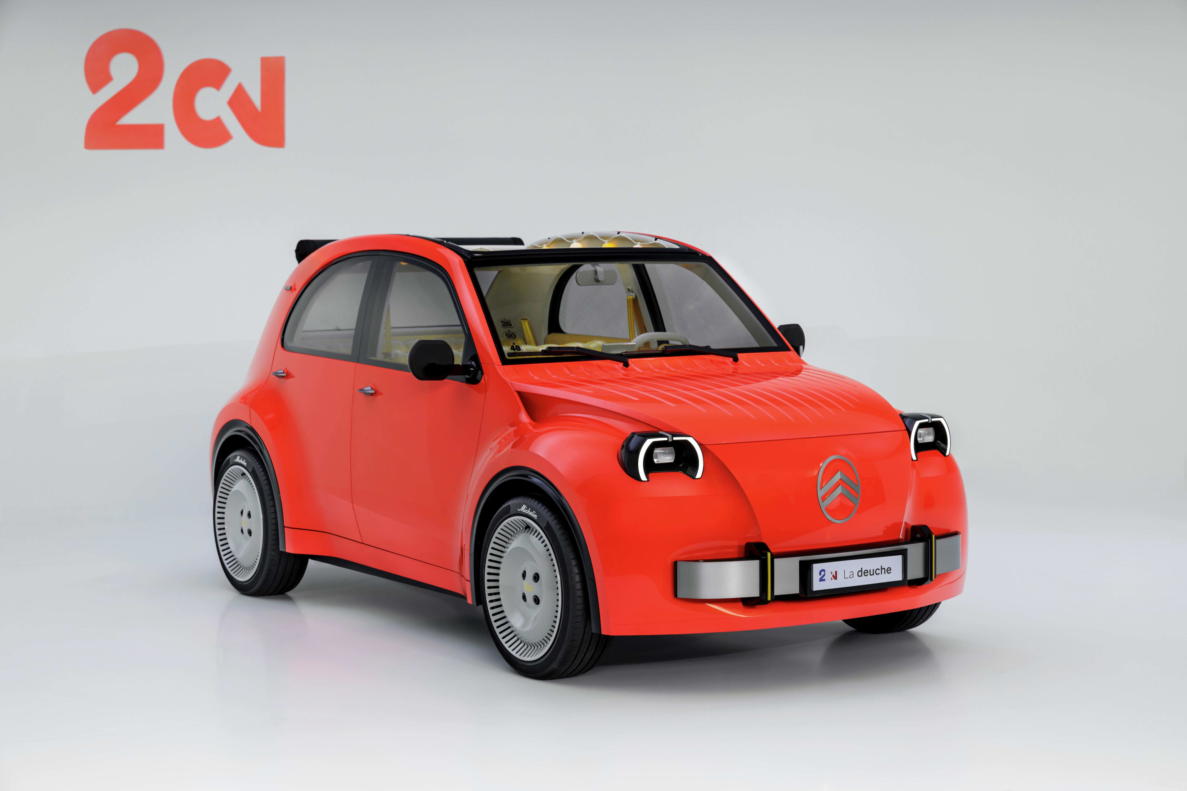 A small red car parked in a white studio.