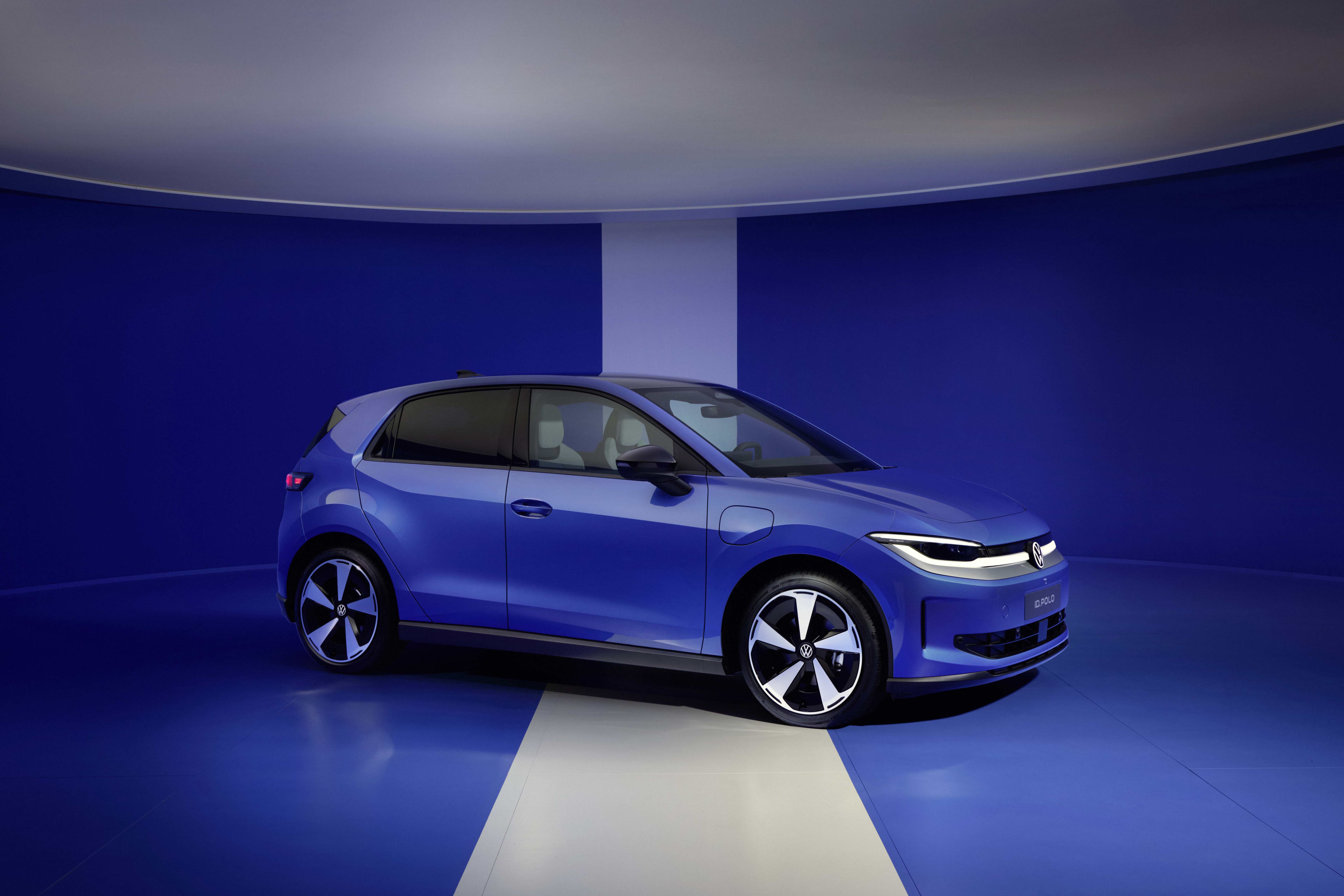 A blue Volkswagen ID Polo in a blue studio, with a white room and white line along the floor.