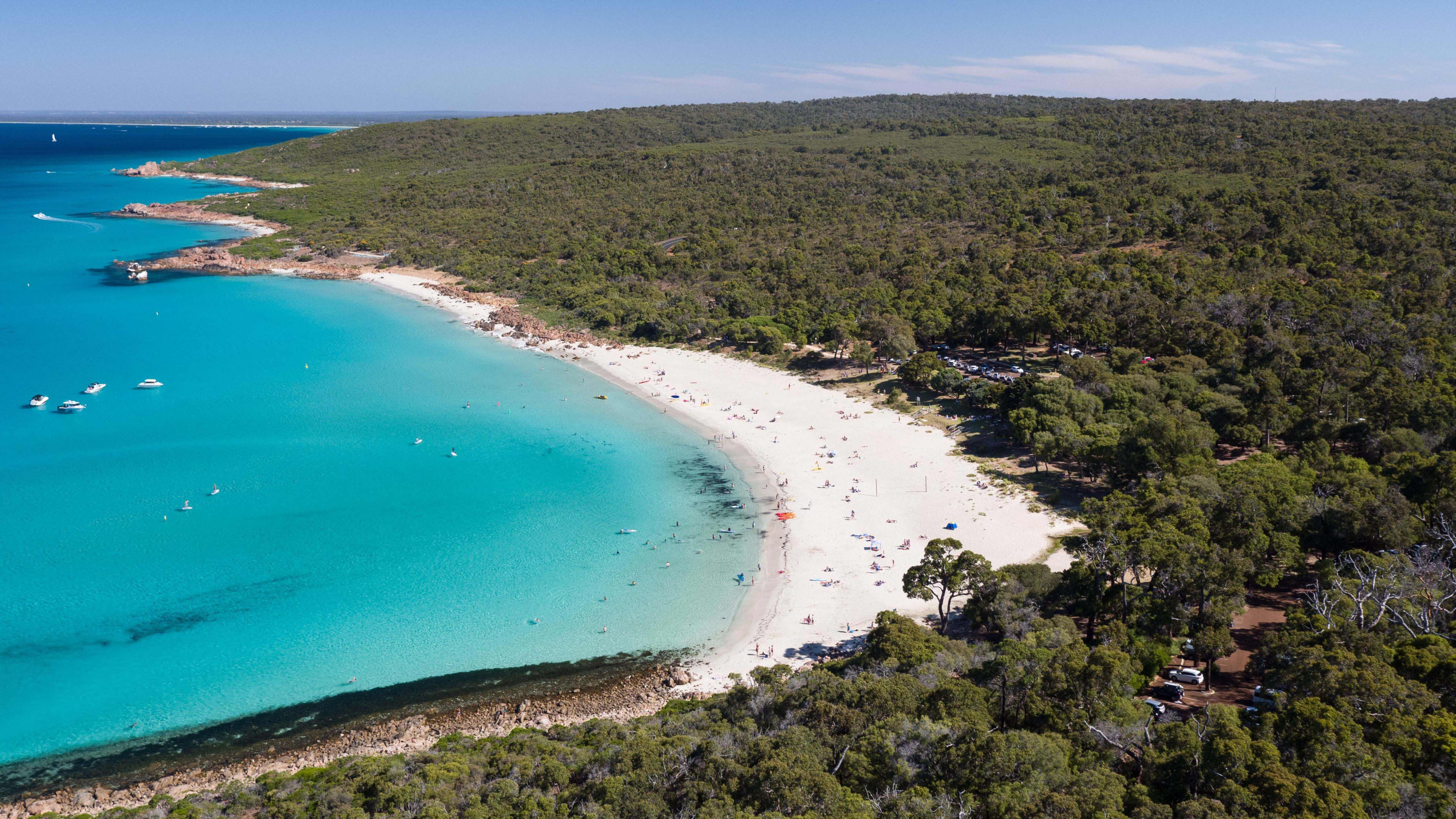 An aerial view showing a white sandy beach and blue ocean in a series of curving bays, with green bushland.
