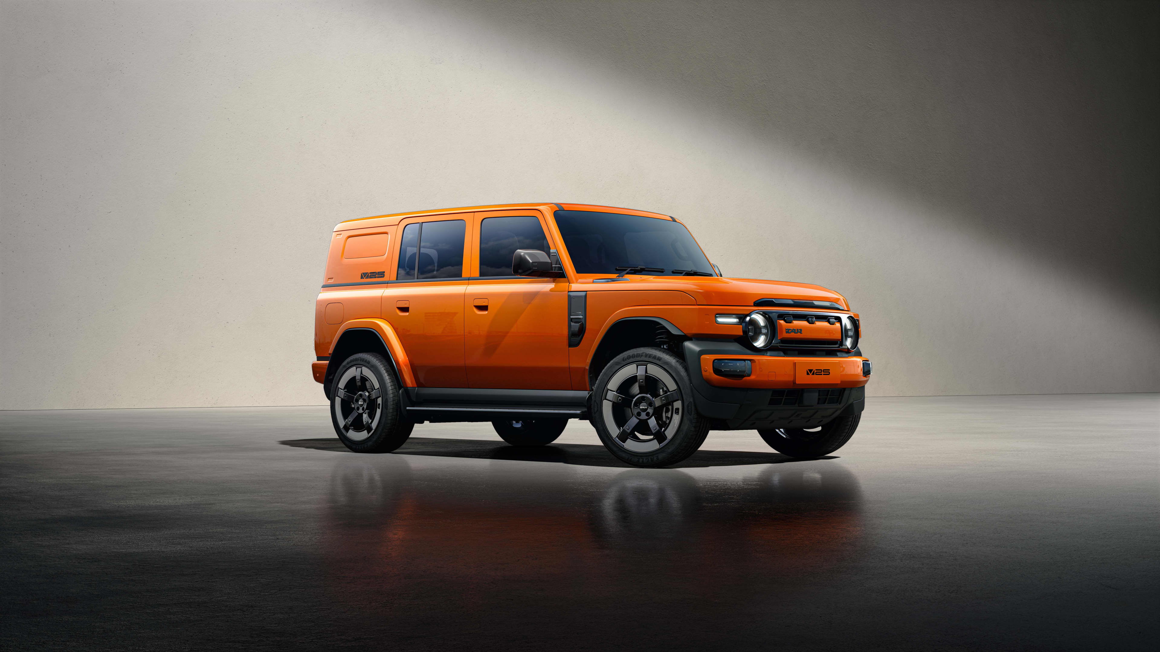 An orange SUV parked in a light coloured studio with spotlight lighting.