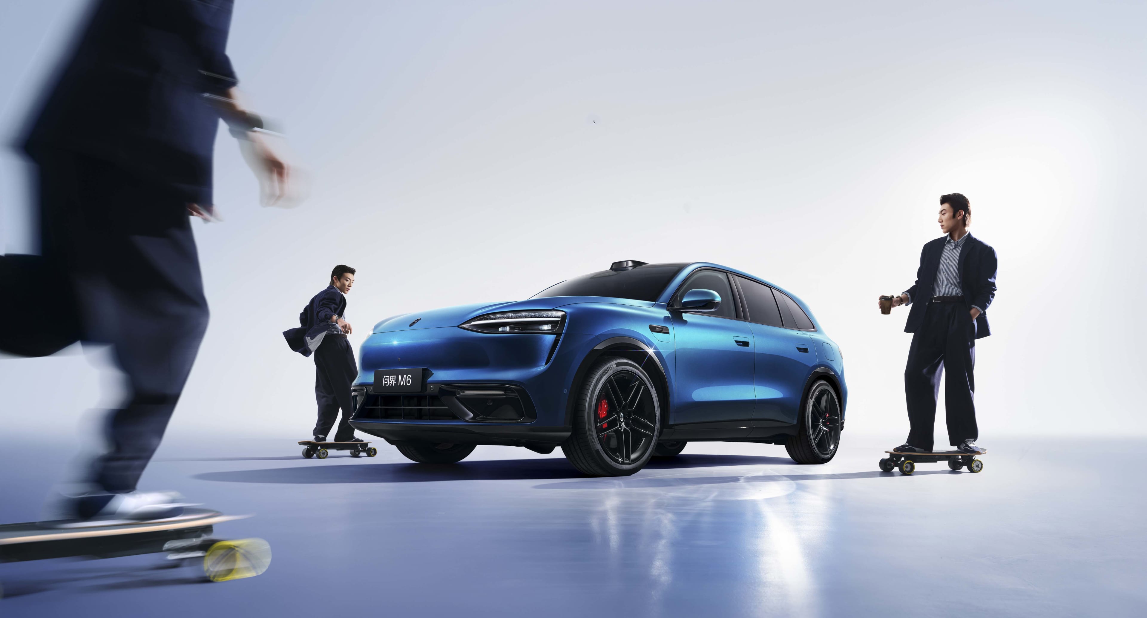 A blue car with people in suits skateboarding around it, in a white studio setting.