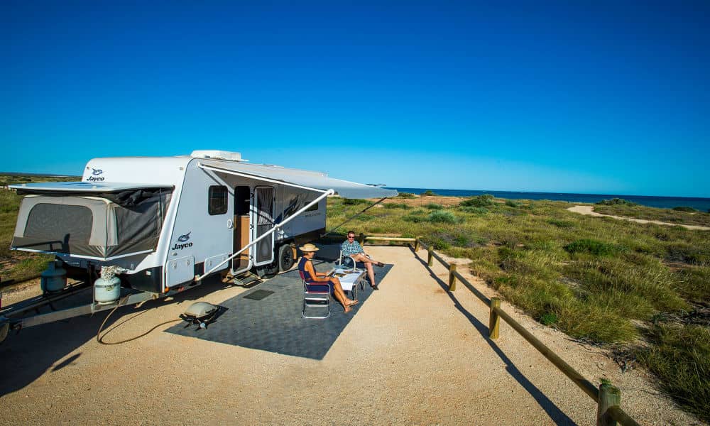 A pair of holidaymakers sitting under the awning of their safely parked caravan