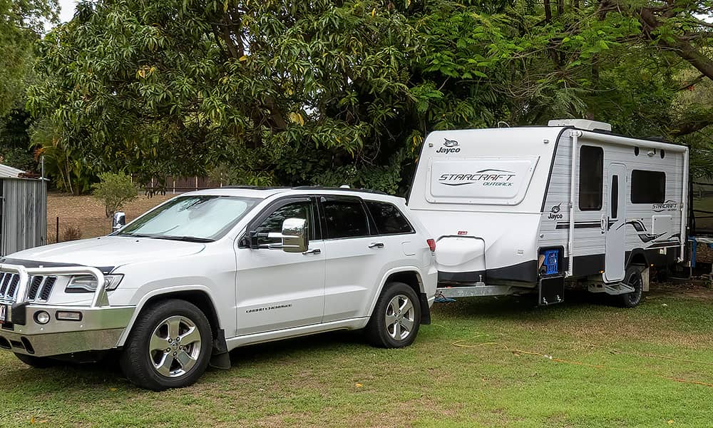 A caravan hitched to  white four-wheel drive in the yard of a home