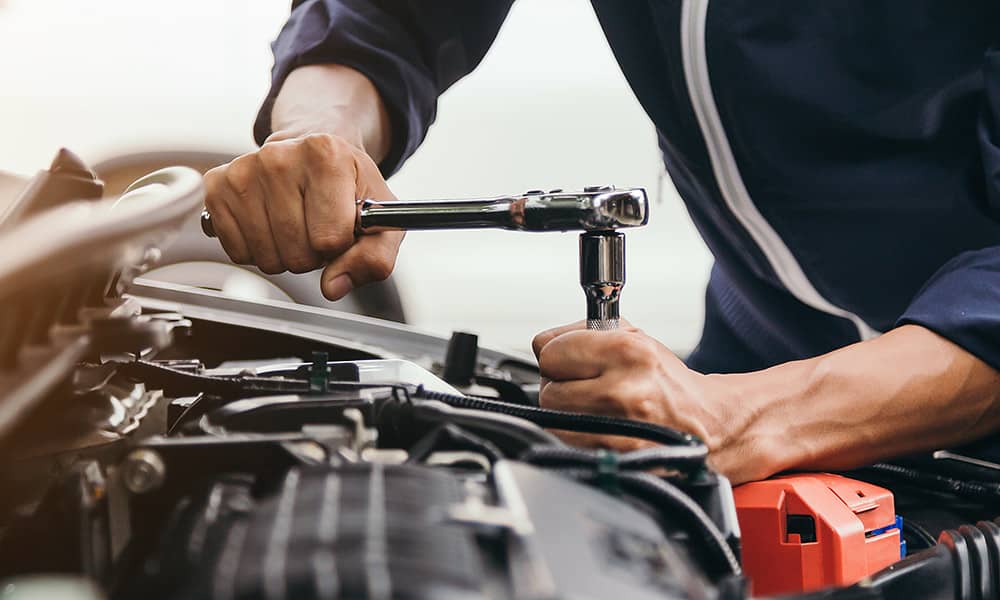 A close up of a person working on a car engine