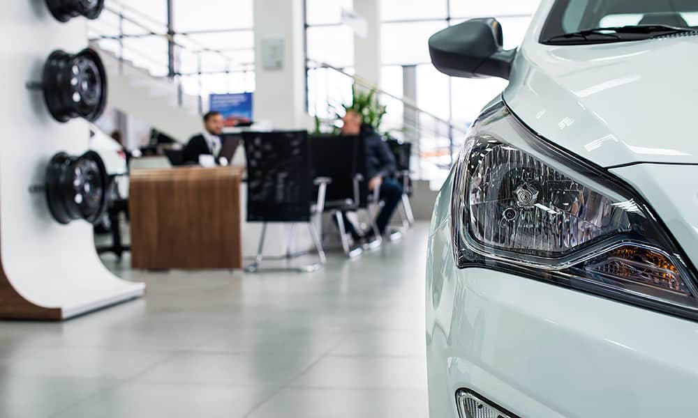Two people at a desk in car dealership showroom