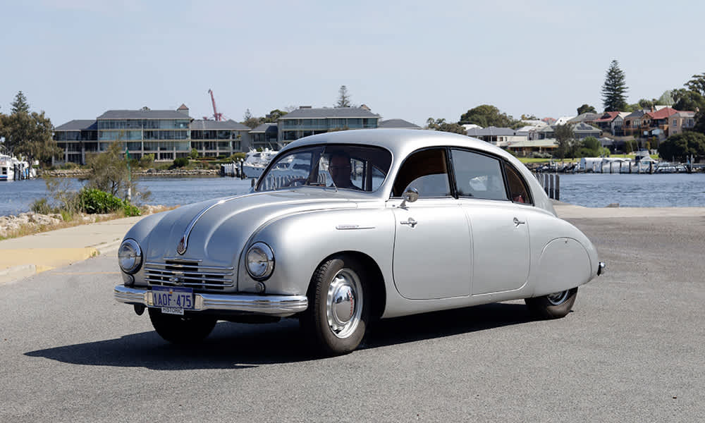 A silver Tatra Automobile parked in front of a river