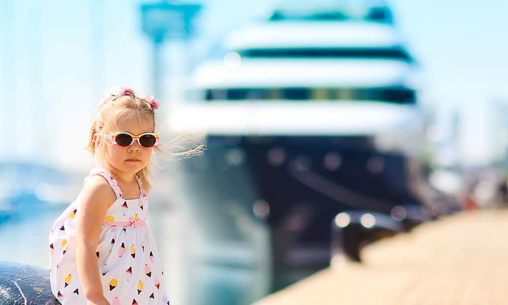 A young girl standing in front of a cruise ship in port