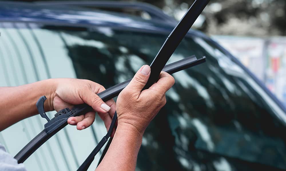 A person is clipping a wiper blade on a windscreen wiper arm