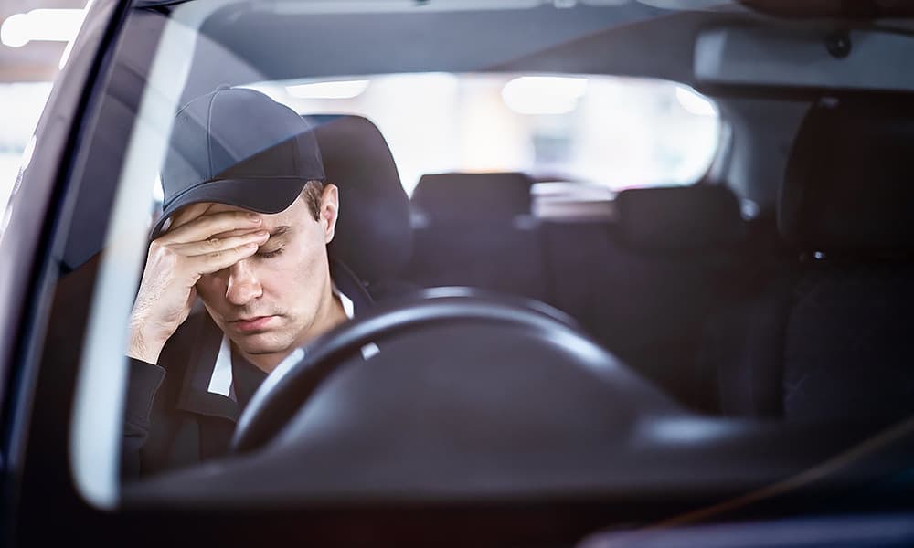 A young male driver with his head resting on one of his hands