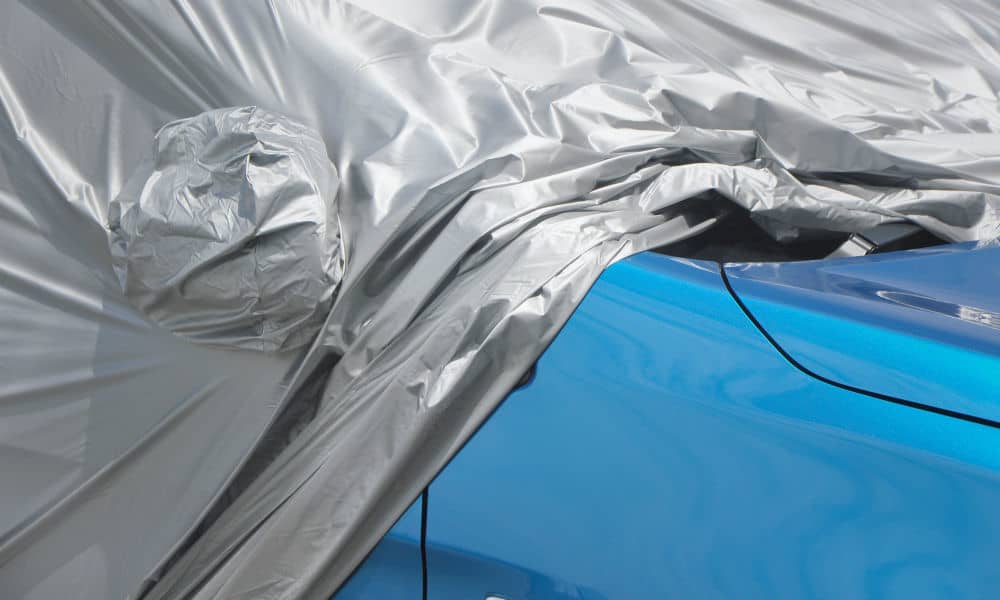 A silver car cover on a blue car