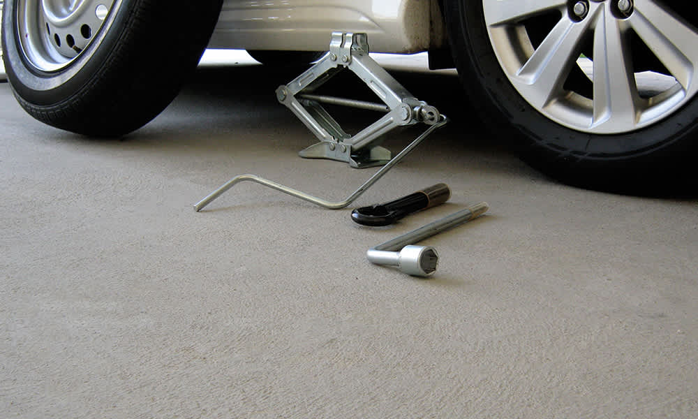 Tools for changing a tyre next to a white car