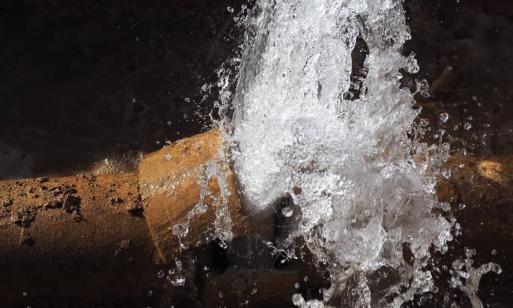 Burst water pipe with water flowing from it