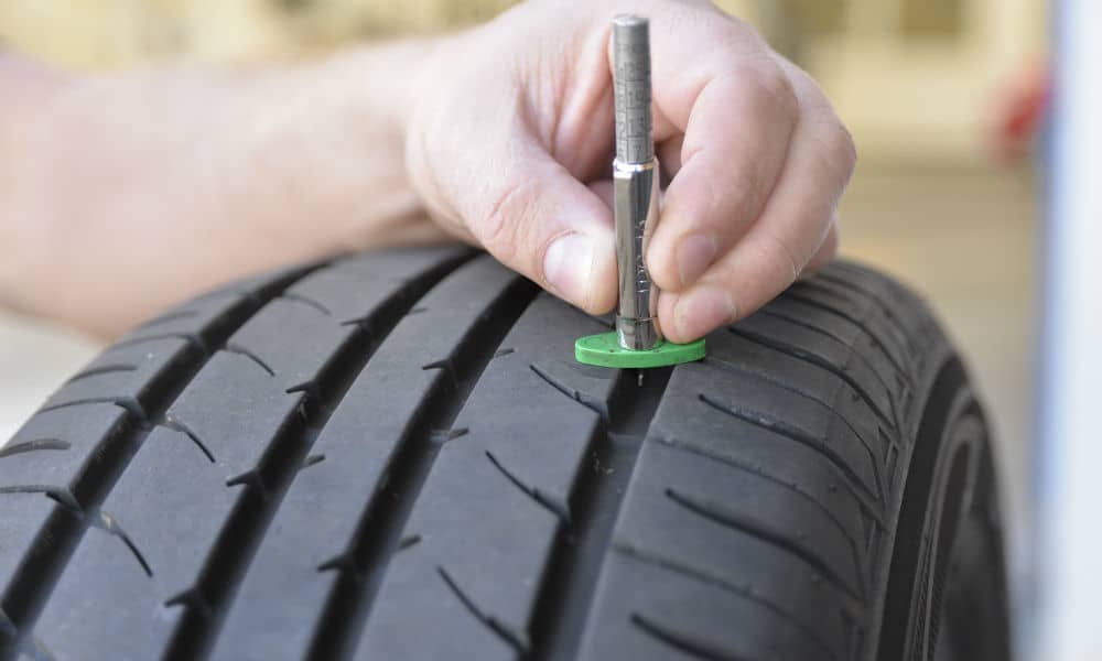 A tyre technician checking the tread of a bald tyre