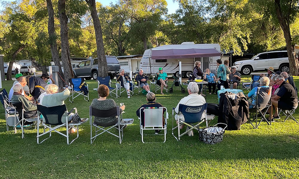 A group of caravanners sitting in a circle socialising in a caravan park