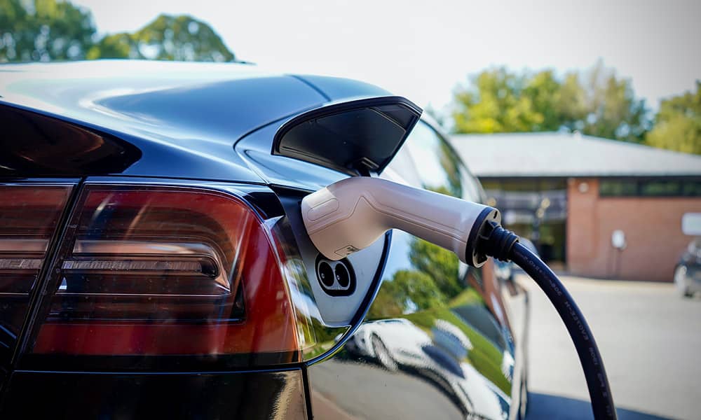 A black electric car being charged outside a home