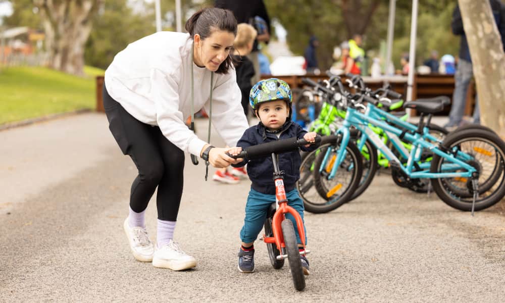 Small child on bike with parent assisting