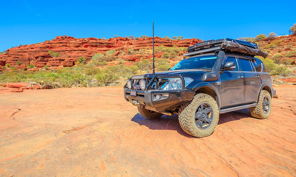A four-wheel drive on a red dirt road