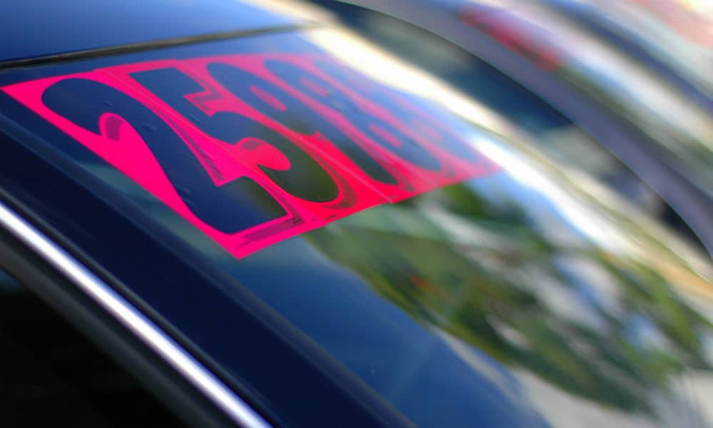 A bright pink sale sticker on a car windscreen