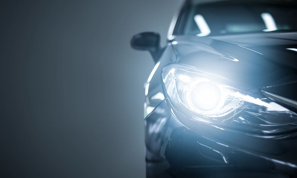 A single car headlight seen against a dark background