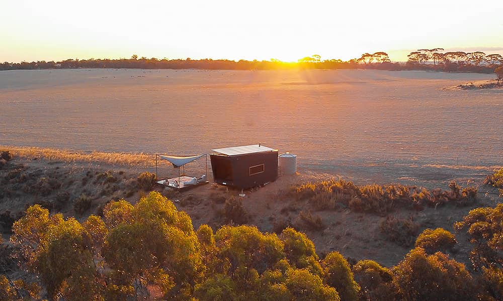 A tiny cabin in Wheatbelt field at sunset