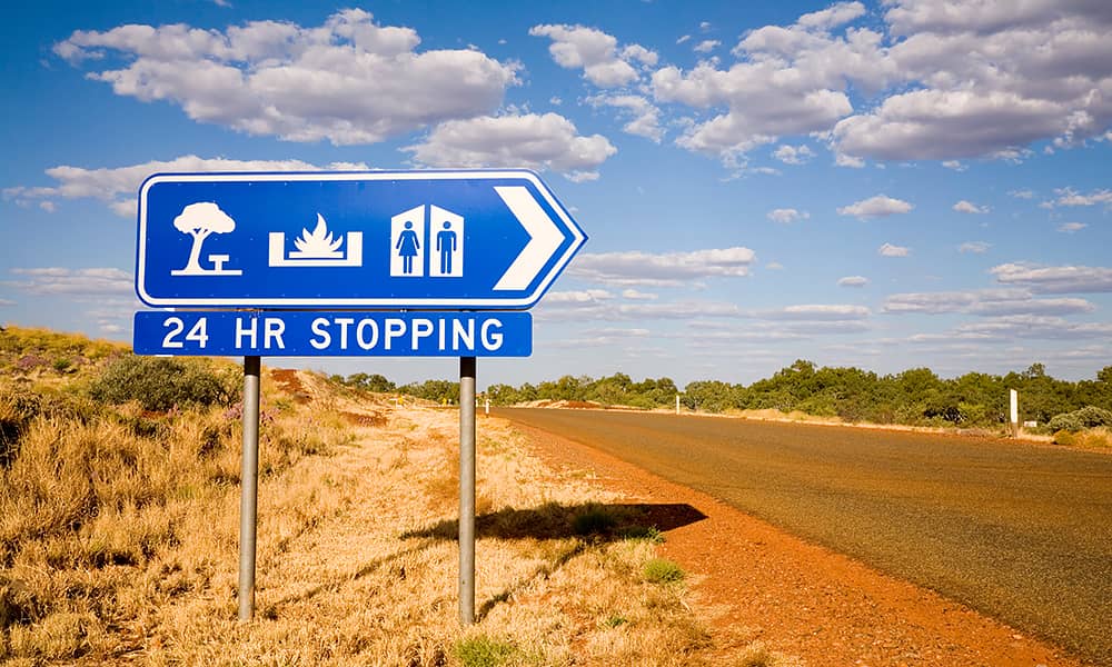 A 24-hour rest stop sign on a country road