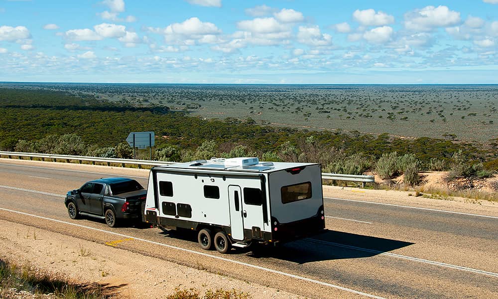 A four-wheel drive towing a caravan along a sealed country road
