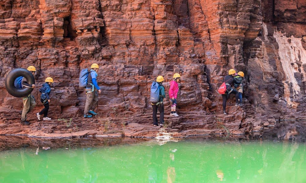 group of adults and children climbing through canyon in Karijini National Park