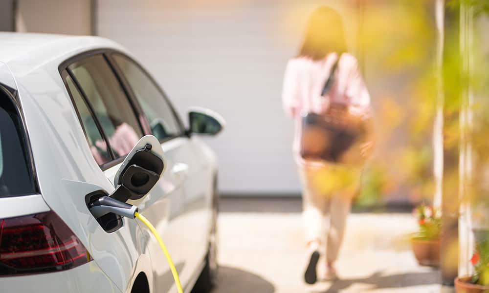 Charging electric car with woman in the background
