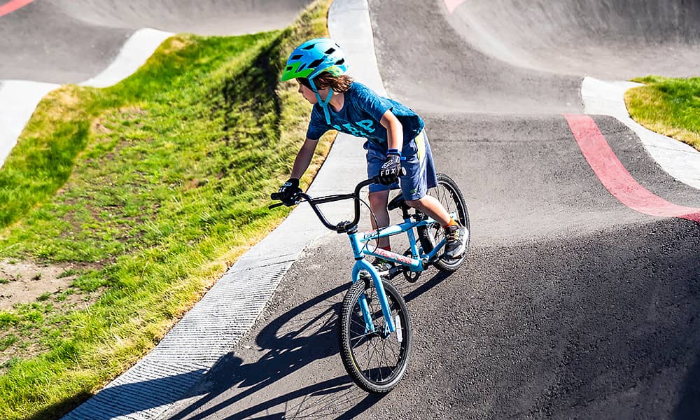 A small child riding a bike around a BMX bike track