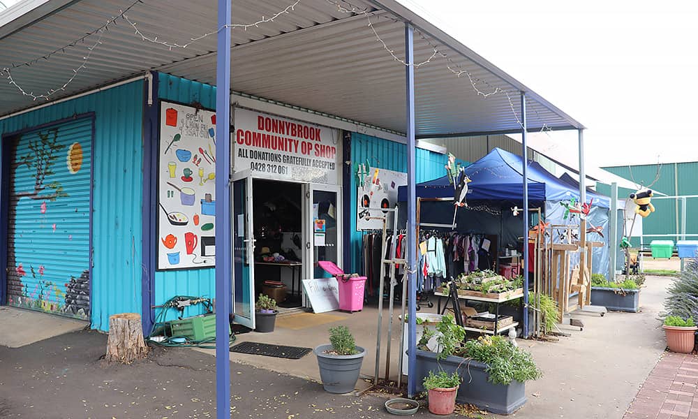 The outside of an op shop painted bright blue with goods outside