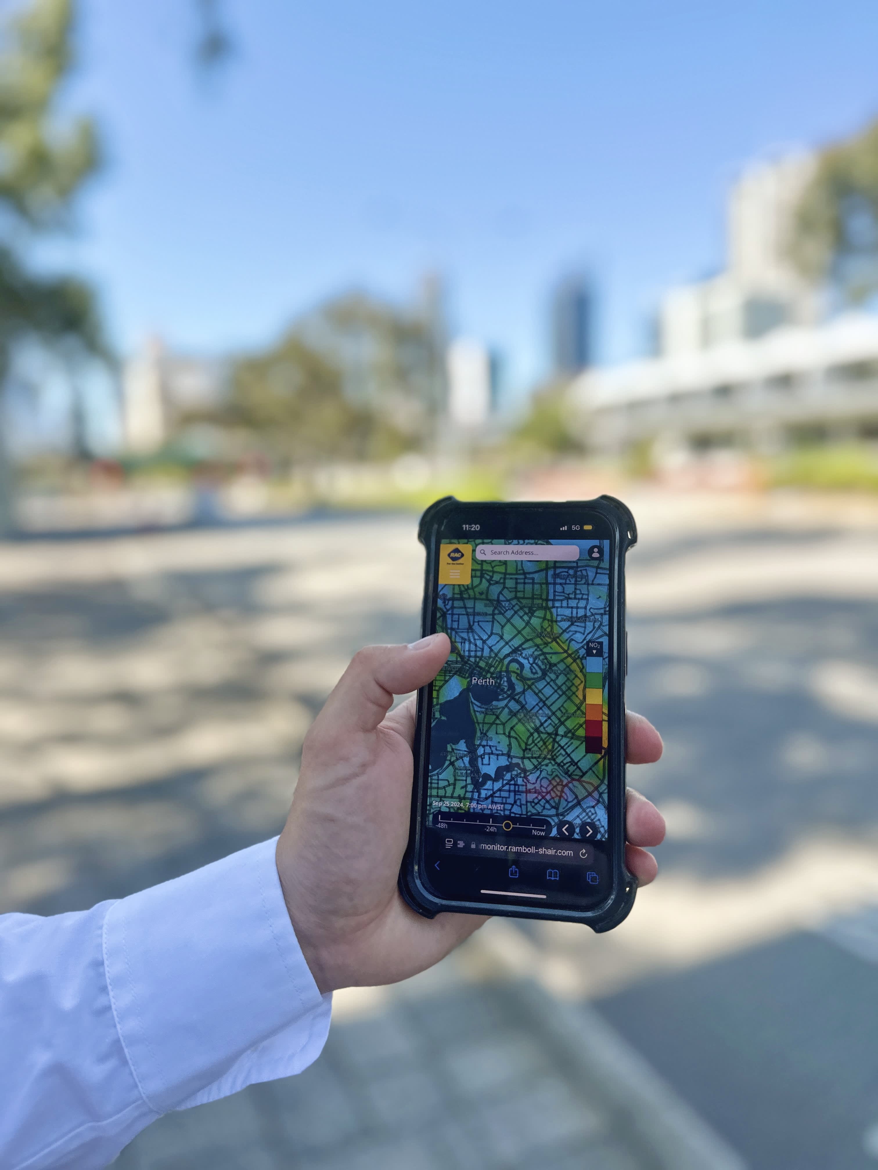 Close-up of a hand holding a phone showing a map overlaid with air health information.