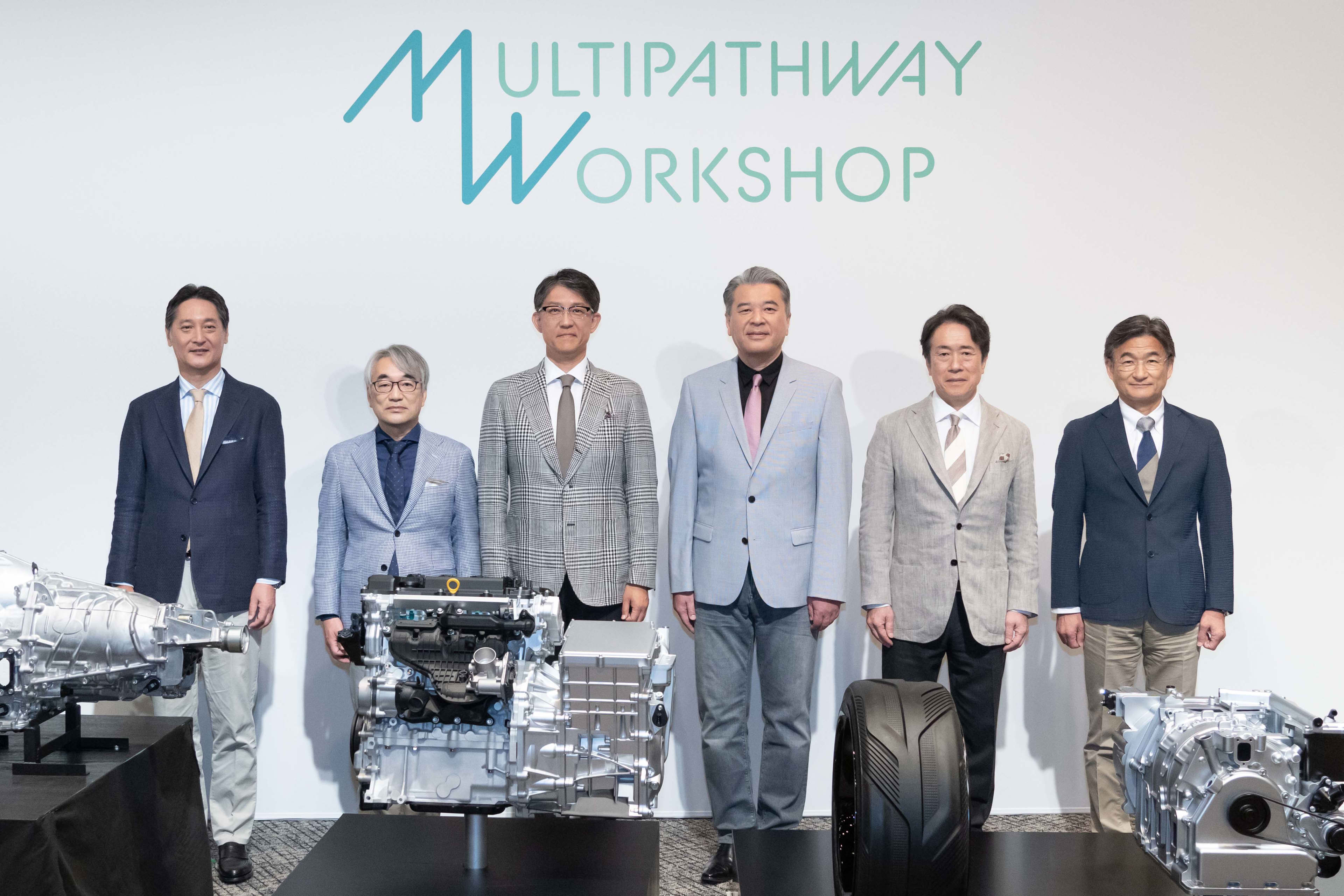 Toyota, Mazda and Subaru executives pose for a photo in front of car engines