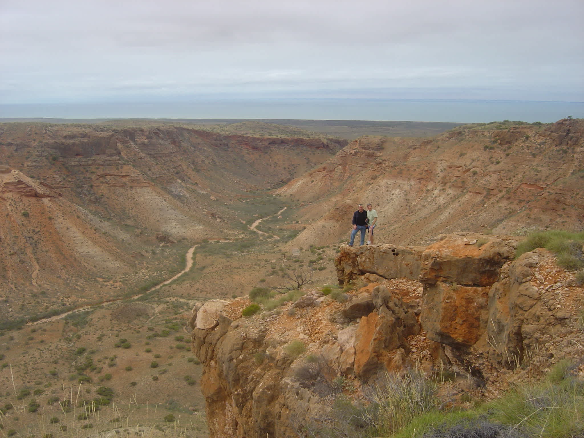 Two hikers standing at the edge of a cliff in Cape Range National Park, Western Australia
