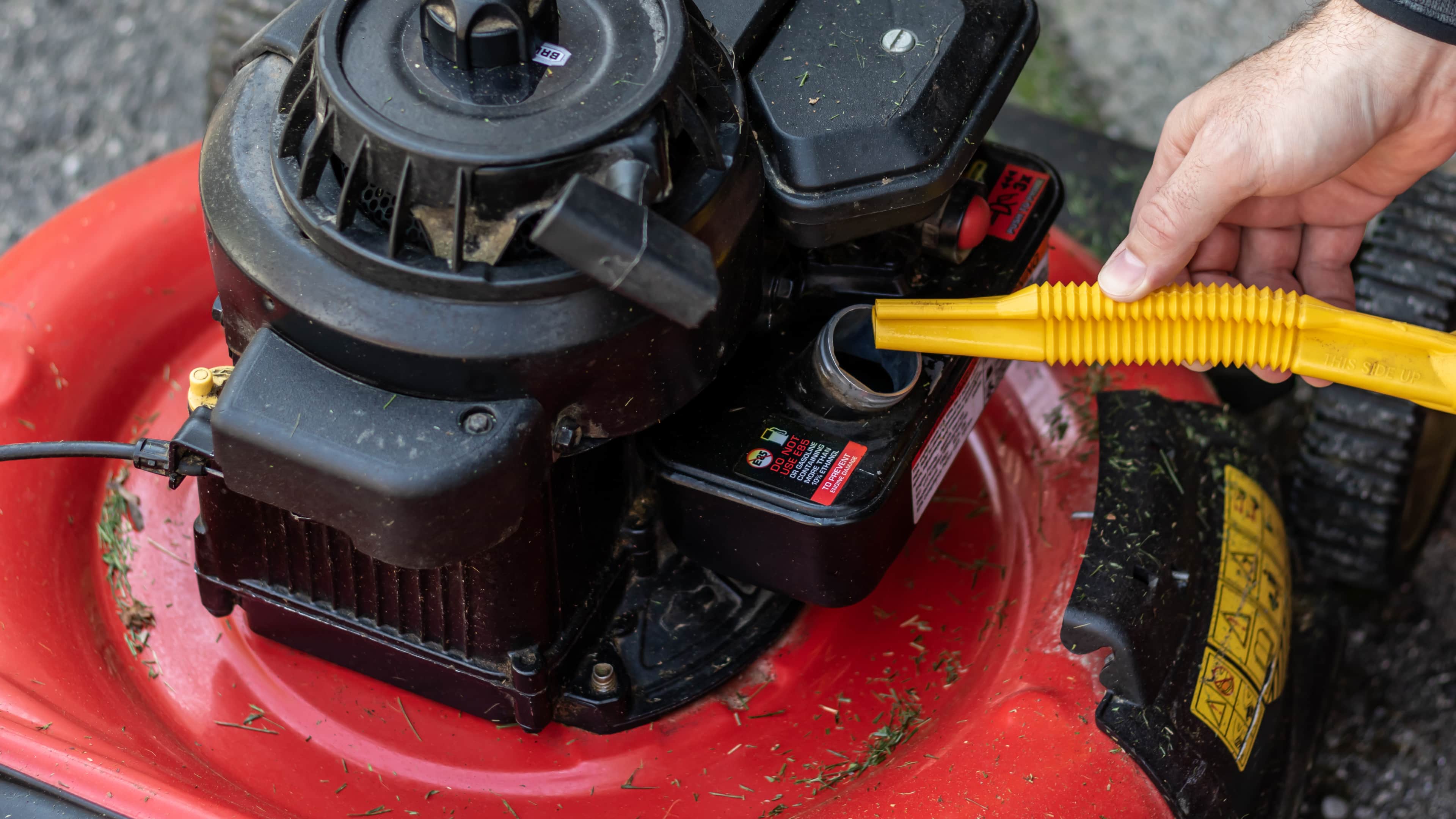 A person is pouring petrol into a lawn mower.