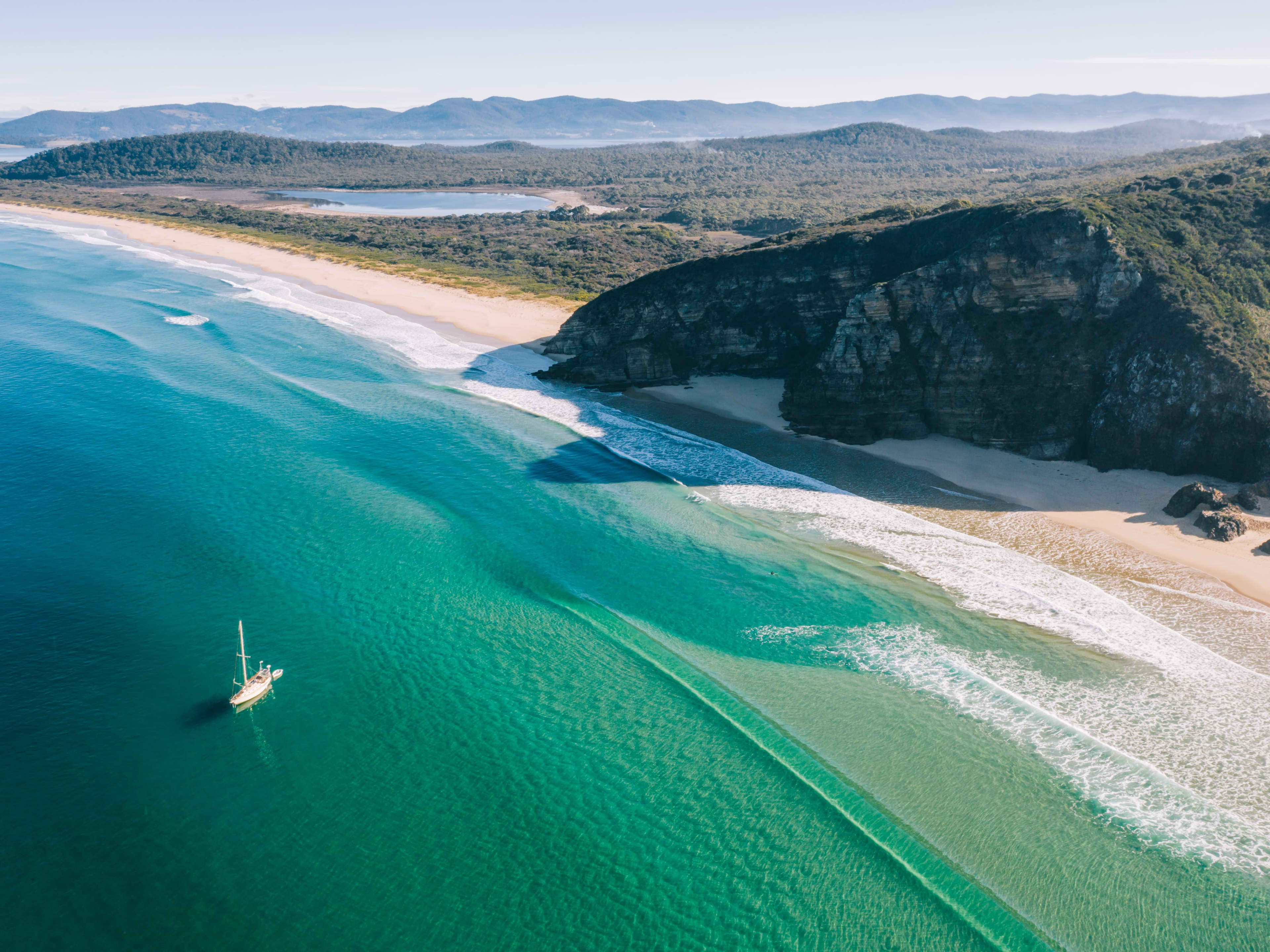 Ocean and cliff views with yacht sailing through turquoise waters