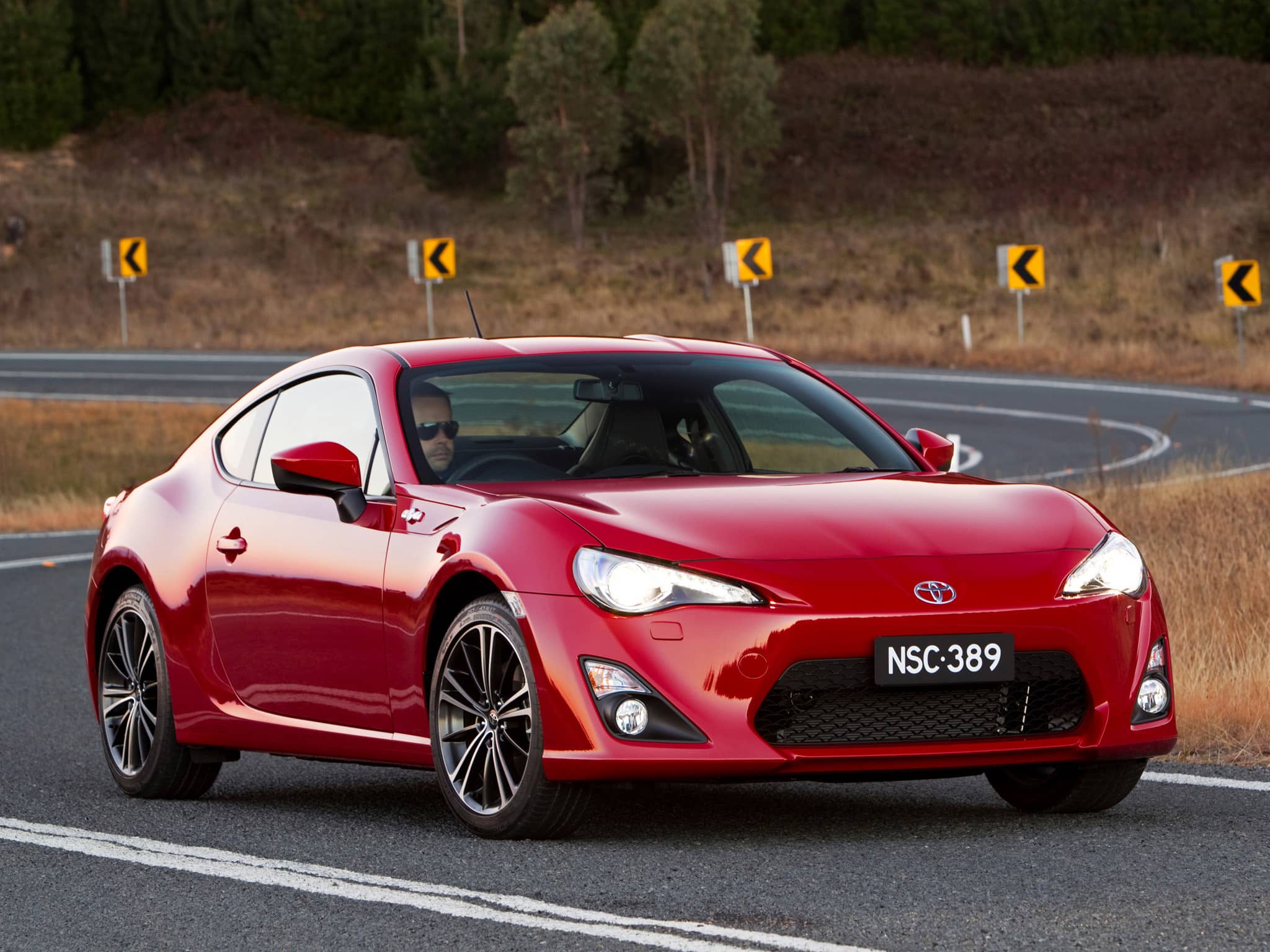 A red 2012 Toyota 86 GTS driving along a regional road
