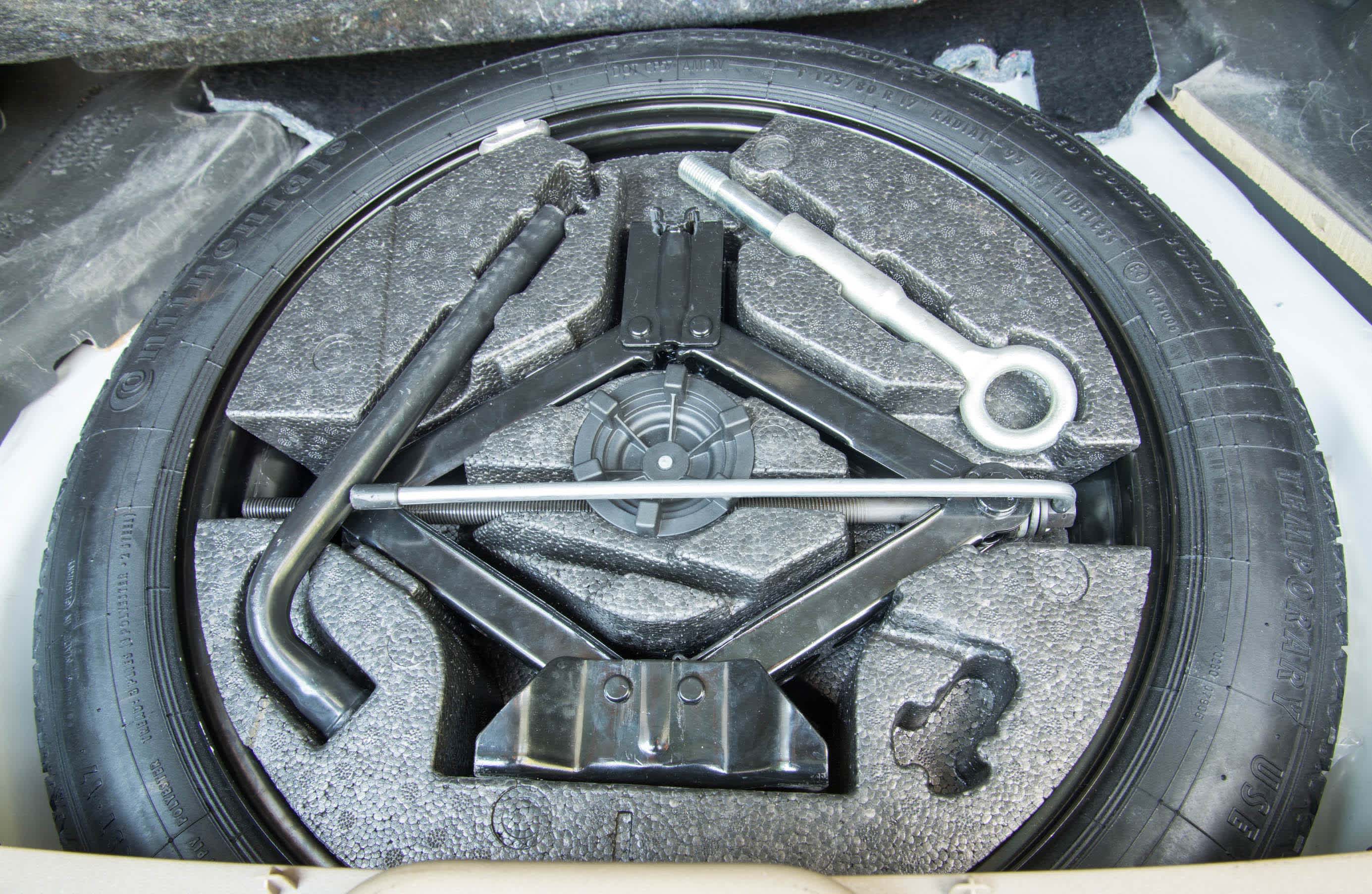 A full-size spare tyre stowed away in a car boot