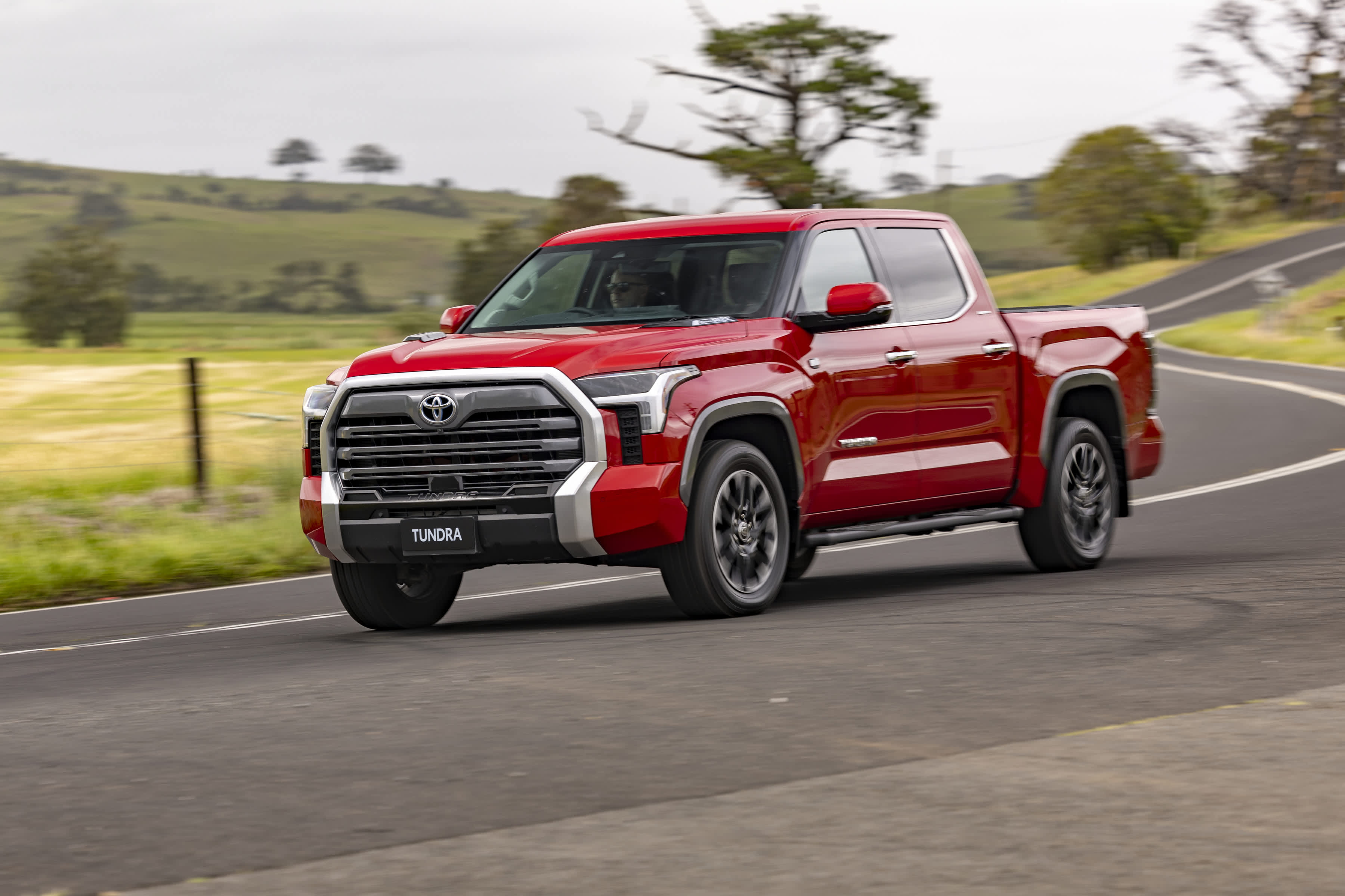 A red Toyota Tundra pickup truck driving on regional Australian roads