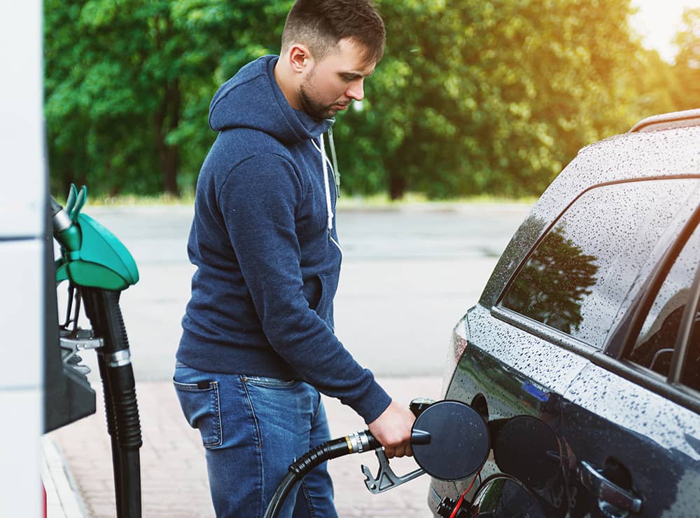A man is filling up his car with fuel at a fuel bowser.