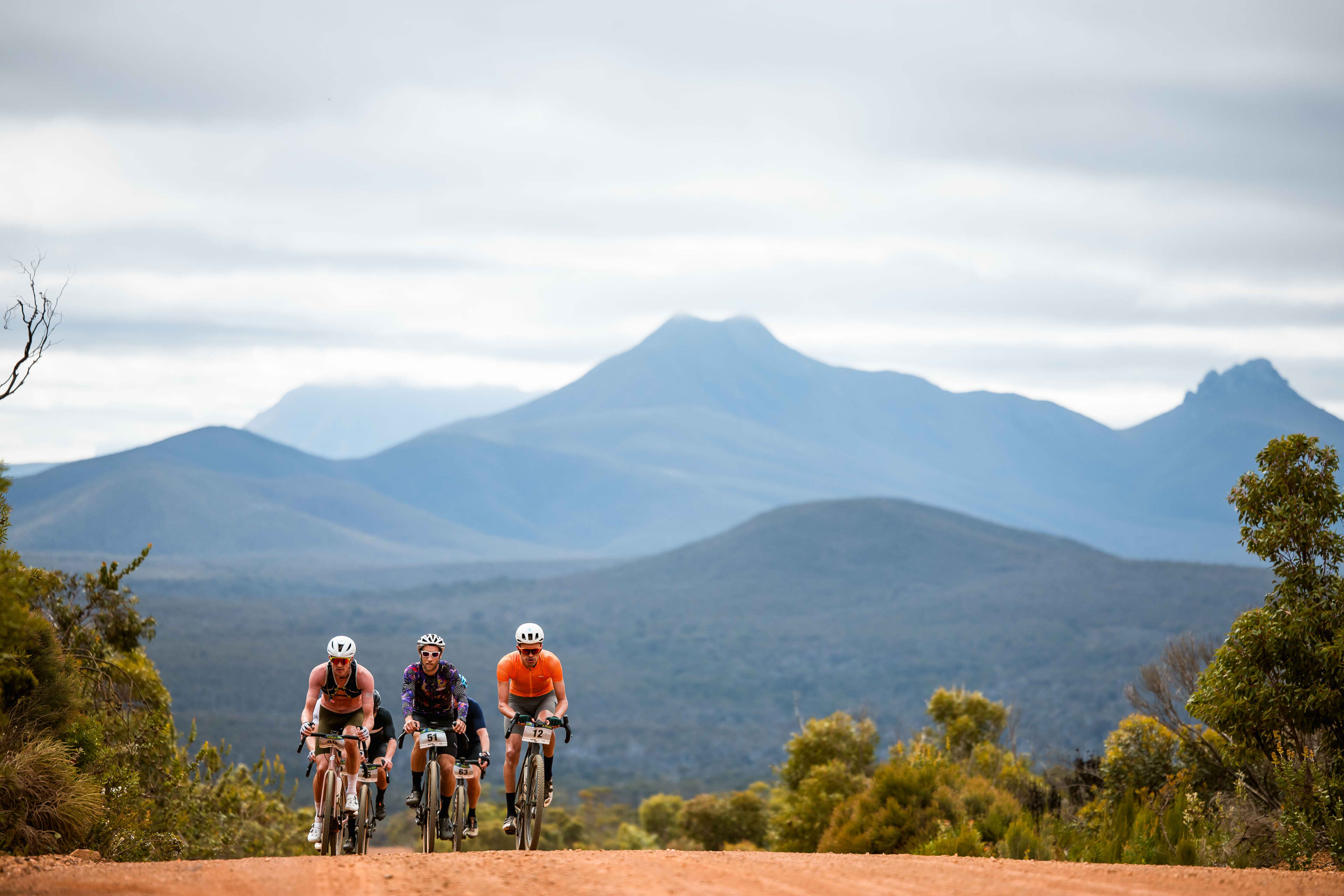 Five people riding bikes along trail with mountains in the background