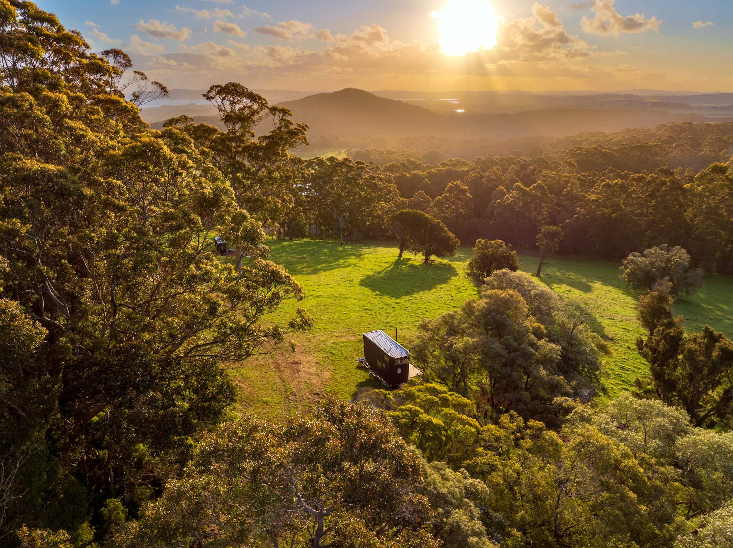 An aerial view of a tiny cabin in a lush green landscape