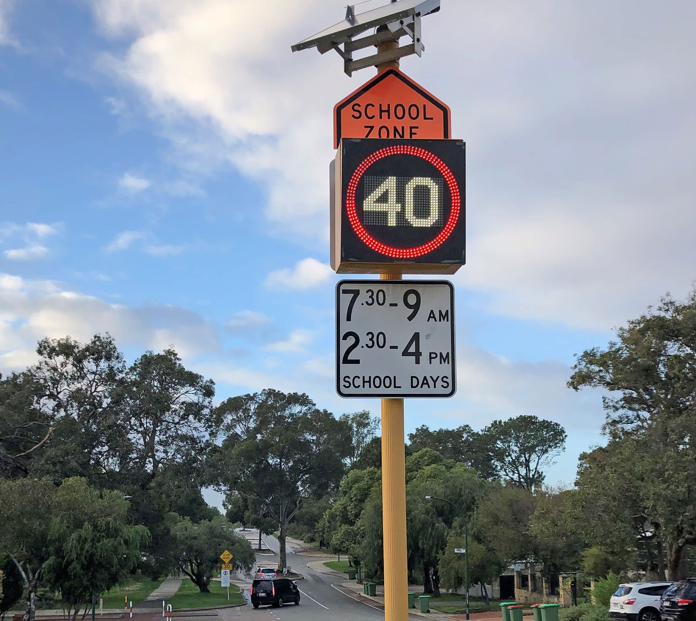 An electronic school zone sign on a suburban street