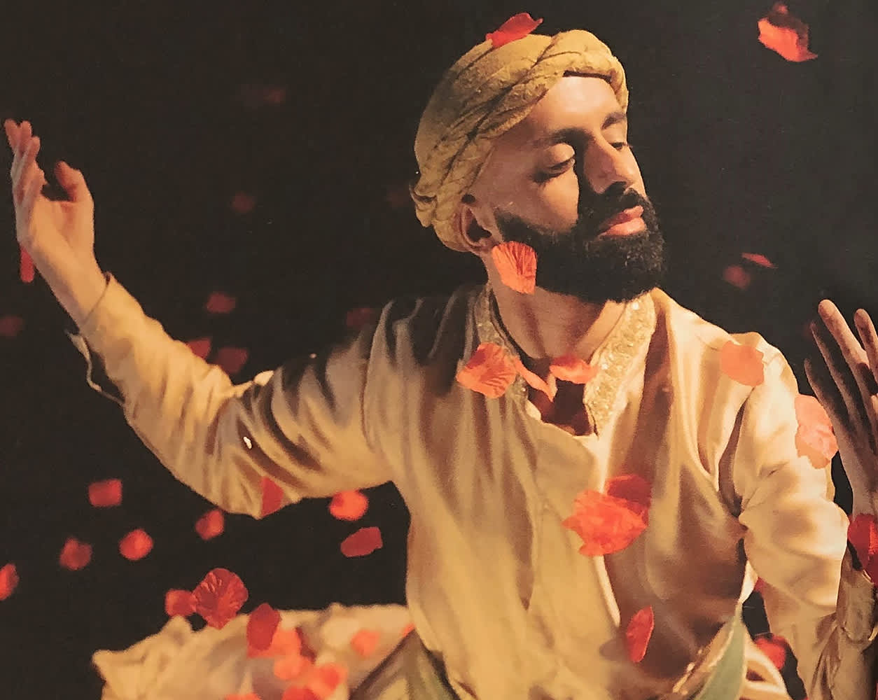 A man is dancing as red petals fall around him.