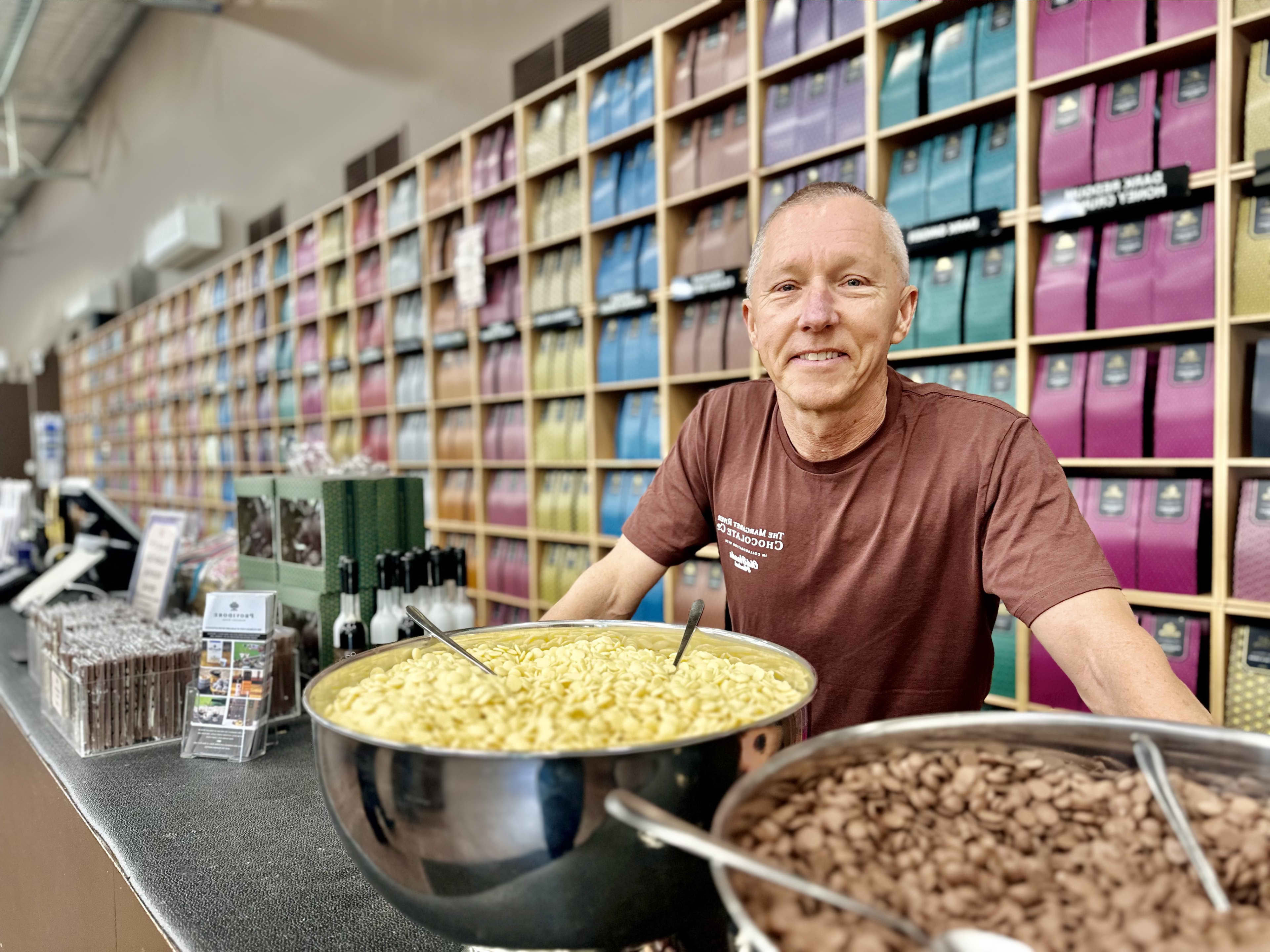 Smiling man standing in front of big bowls of chocolate samples