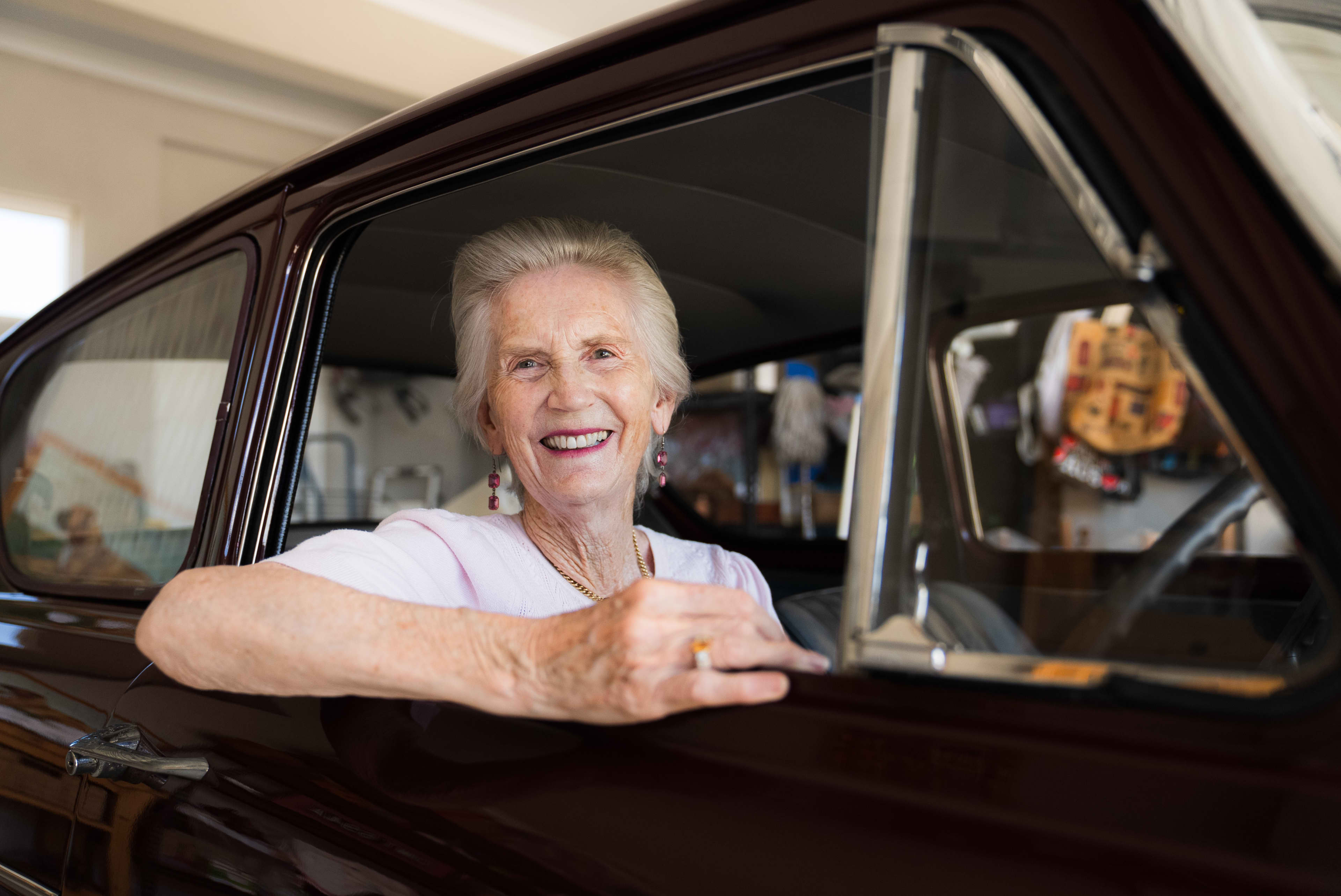 Woman sitting and smiling out of the window from the driver's seat of her car