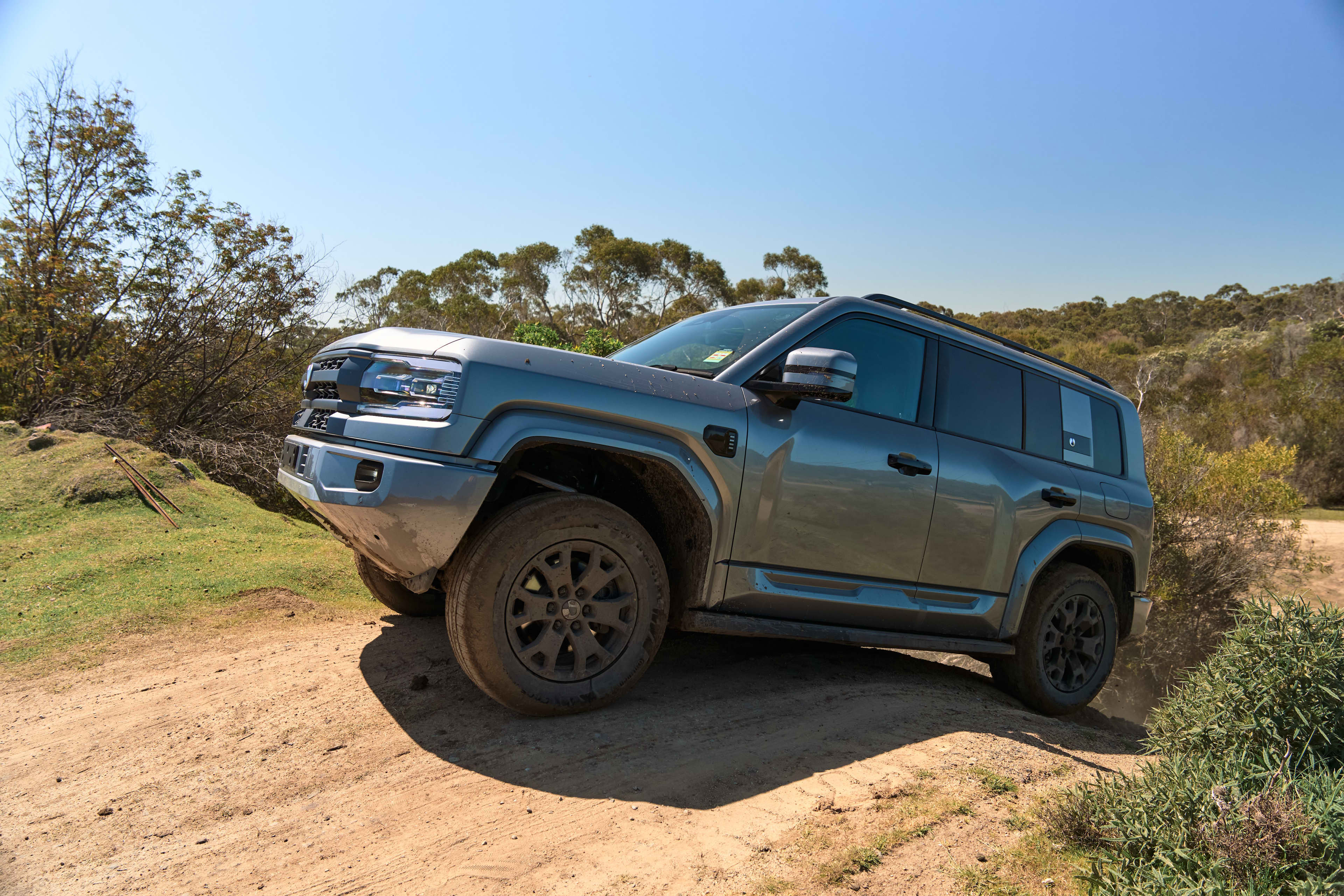 A grey BYD Denza parked on a sandy hillside