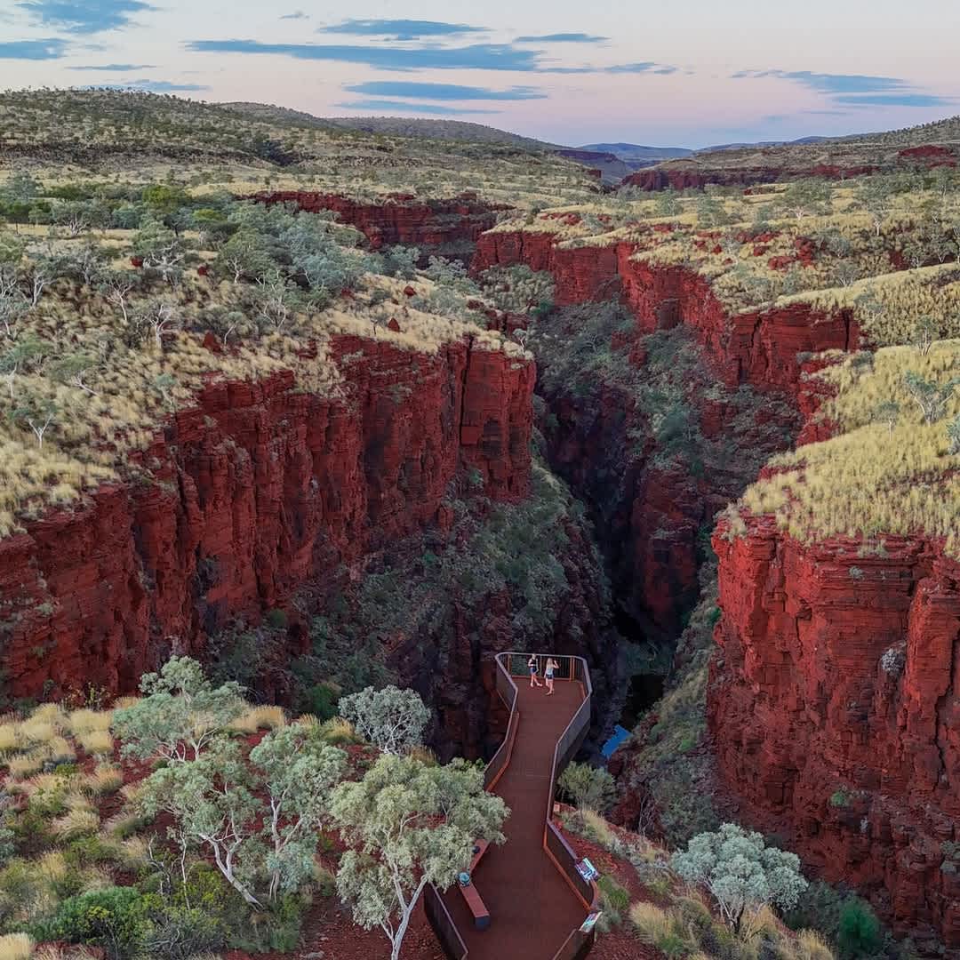 An ochre gorge winding, with a suspended lookout with two people standing.